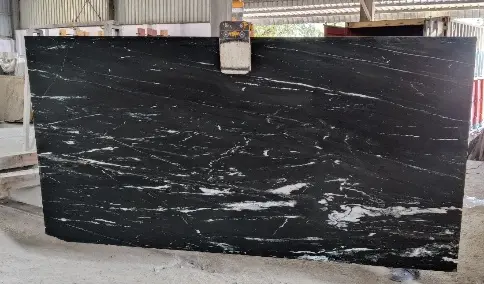 A large slab of black granite being safely lifted by a vacuum lifter and crane
